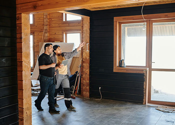 Two men discussing features inside a wooden cabin, highlighting wildest things the rich can purchase unknown to poor people.