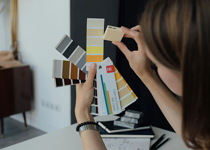 Person holding and comparing color swatches, exploring wildest things the rich can purchase and unique luxury items.