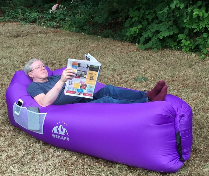 Man relaxing on a purple inflatable lounger in backyard, enjoying outdoor upgrades for the ultimate summer hotspot.