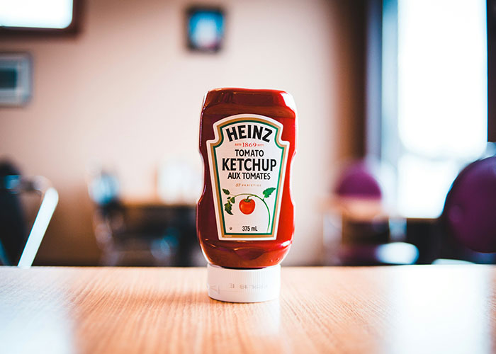 Heinz tomato ketchup bottle on a wooden table, representing unfiltered food opinions and crunchy vinegar debates.
