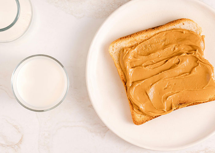 Peanut butter spread on toasted bread on a plate with a glass of milk, representing unfiltered food opinions.