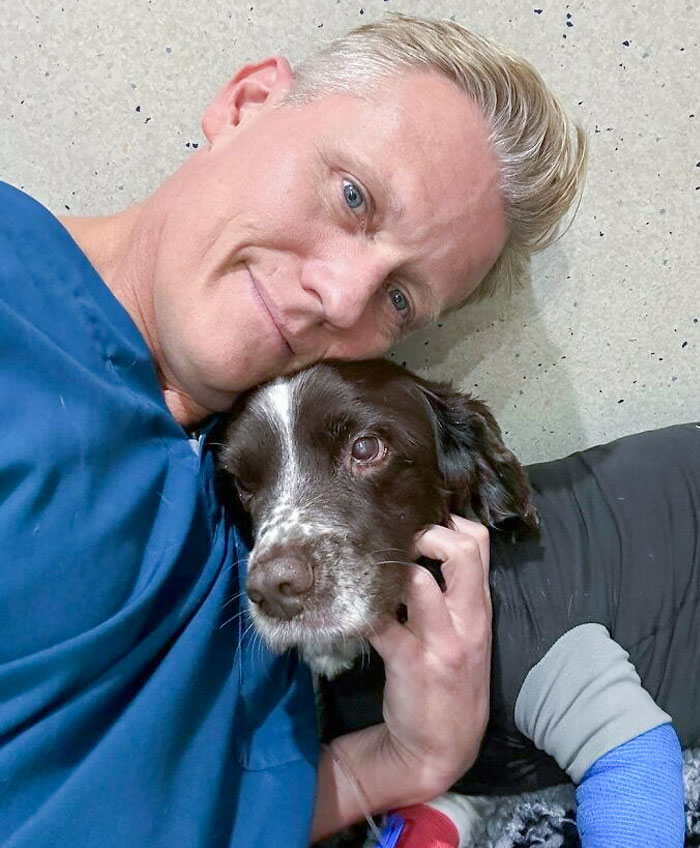 Vet cuddling with a dog in a tender moment at the clinic.