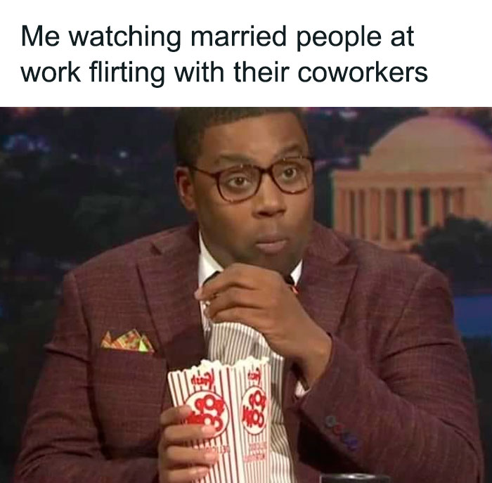 Man in glasses with popcorn, watching work memes unfold humorously.