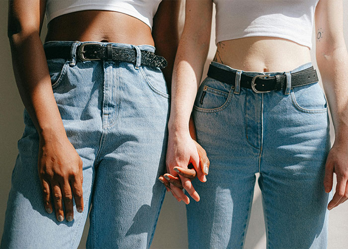 Two people holding hands wearing high-waisted jeans and white tops representing strange childhood realities.