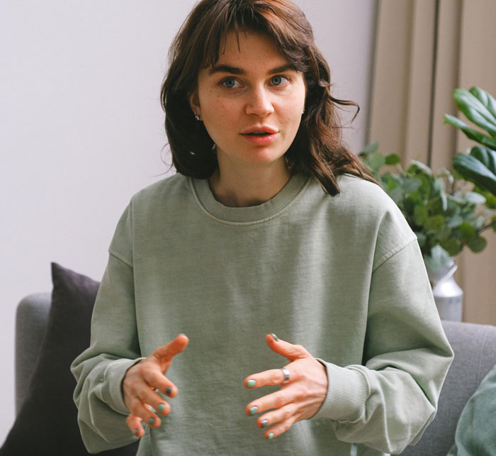 Woman expressing emotions while speaking, sitting on a couch on Mother's Day.