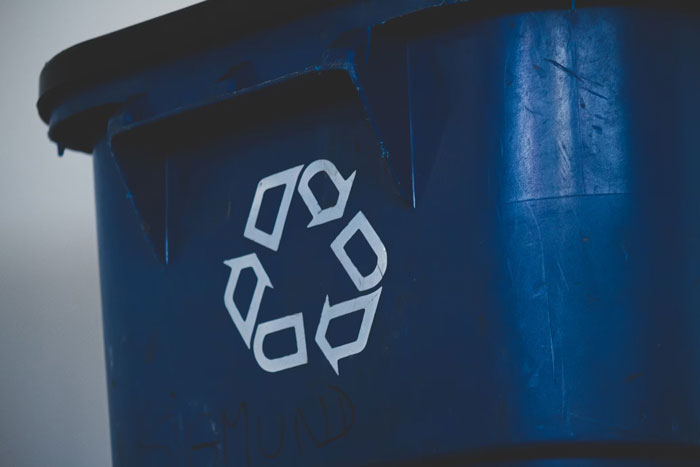 Blue recycling bin with a white recycling symbol on the side.