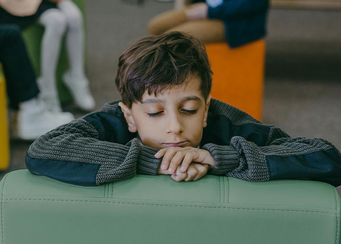 Young boy resting on a green couch, reflecting on strange childhood realities that many later learned were not normal.