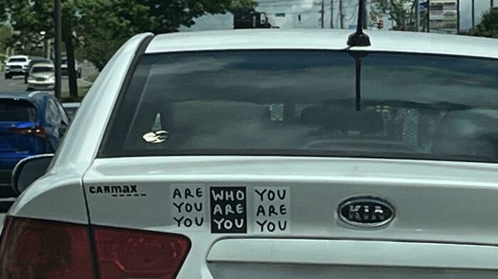Car with a confusing message sticker that reads "ARE YOU WHO YOU ARE YOU" on the trunk. Sign fails in action.