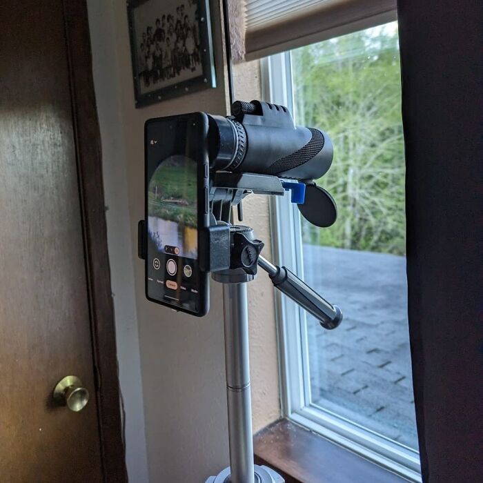 Smartphone attached to a novelty telescope setup by a window, providing a dopamine hit with unique viewing experiences.