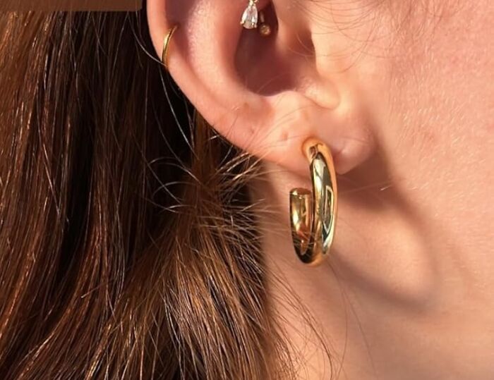 Gold hoop earrings, a cheerful Mother's Day gift under $20, worn by a woman.