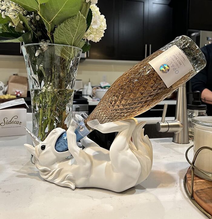 White unicorn bottle holder on a kitchen counter holding a wine bottle, showcasing one of 50 random genius things.