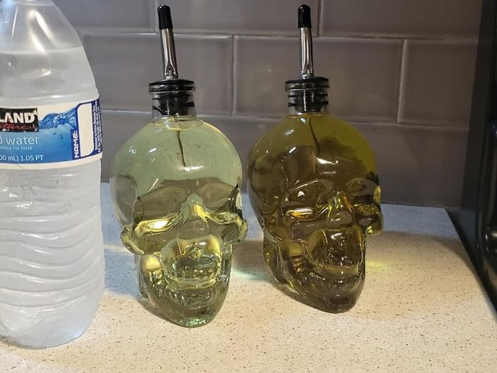 Two skull-shaped bottles filled with liquid placed on a kitchen counter, showcasing creative random genius design.