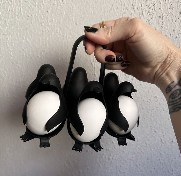 Penguin-shaped egg holder, a weird kitchen item that holds three eggs, being displayed by a hand.