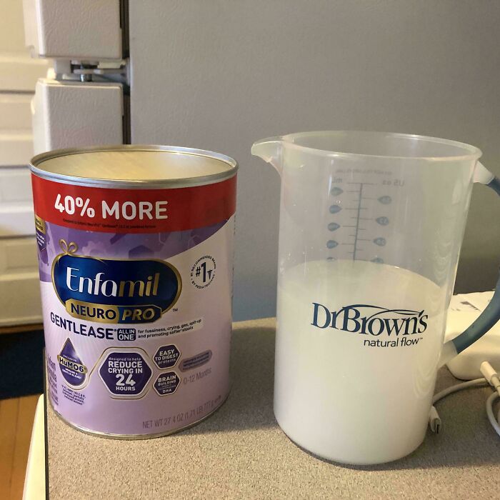 Can of baby formula next to a Dr. Brown's measuring cup filled with milk, capturing a dad moment.