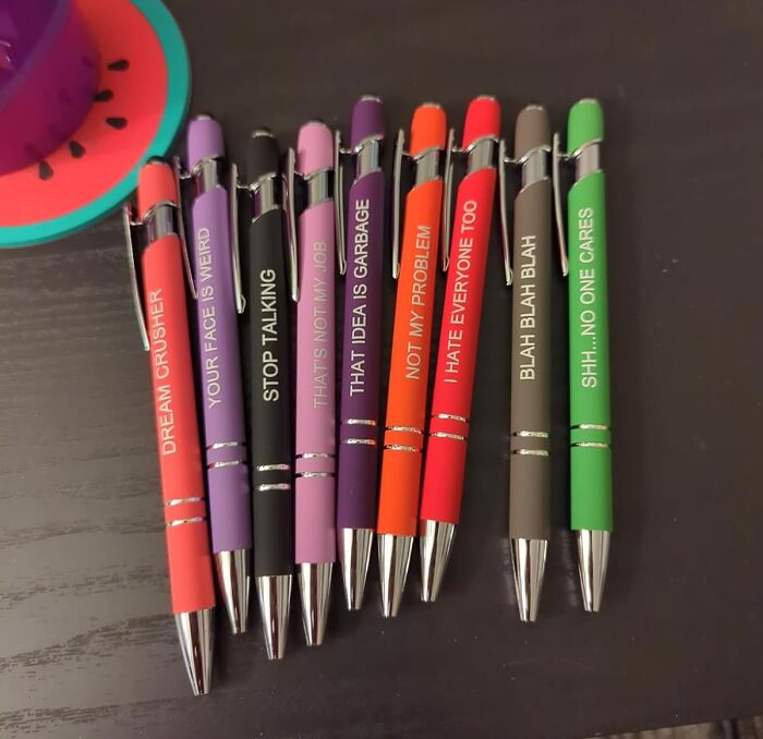 Colorful novelty pens with funny phrases displayed on a dark surface, trending products in the Pandaverse virtual market.