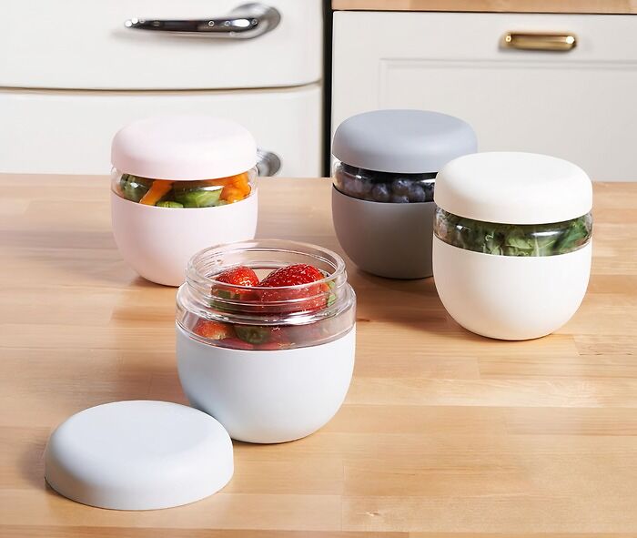 Containers on a kitchen counter filled with fresh fruits and vegetables, perfect for reinventing your fridge and pantry organization.