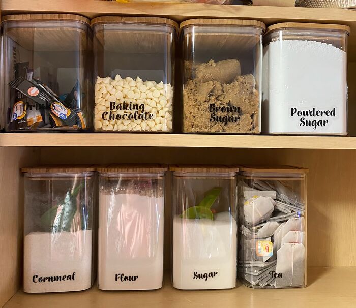 Organized pantry with labeled containers for baking chocolate, brown sugar, cornmeal, flour, sugar, and tea.