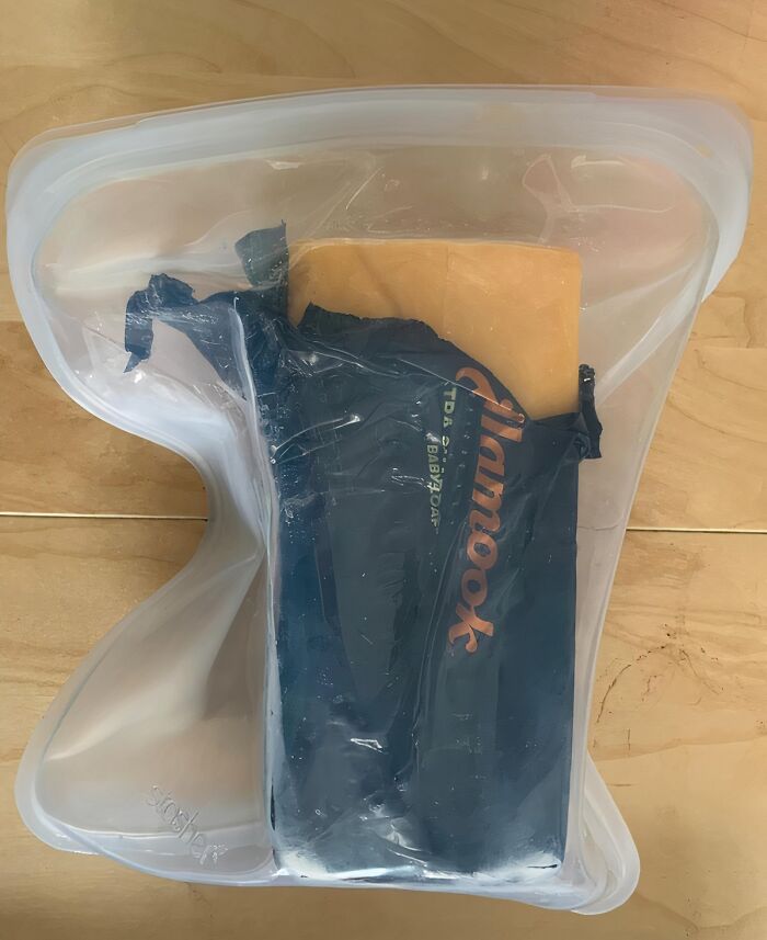 Reusable silicone storage bag holding cheese package, ideal for reinventing fridge organization.