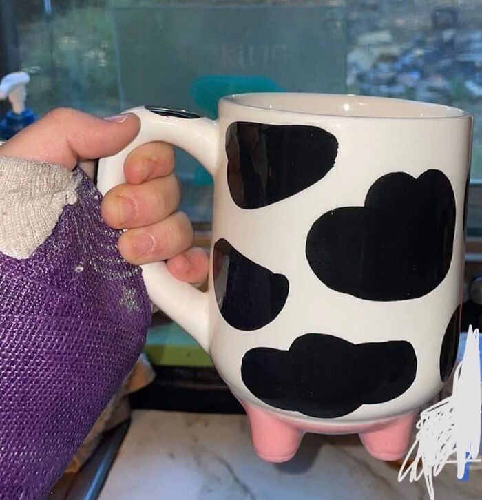 Hand holding a cow print mug with four small legs, showcasing one of the random genius things people want.