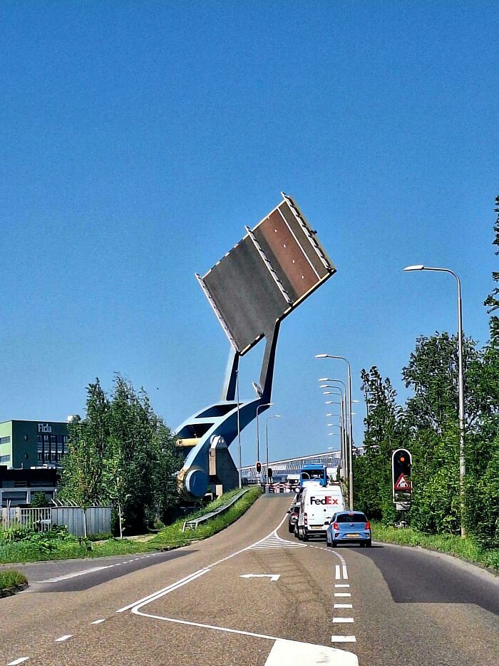Modern infrastructure with a raised bascule bridge allowing vehicles to pass under clear blue sky on a sunny day