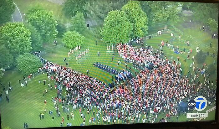 A large crowd gathered in a park around a stage during an outdoor event capturing funny and awkward moments attempt.