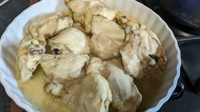 Bland cooked chicken pieces in a white dish, highlighting unusual dish preparation.