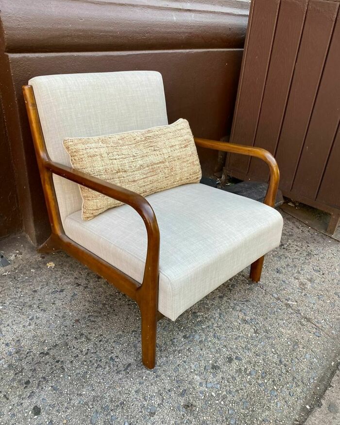 Vintage chair with wooden arms and a beige cushion found on the curb in NYC.