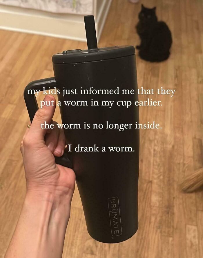 Hand holding a black tumbler with text about kids putting a worm in a cup, depicting a parent having a pretty miserable day.