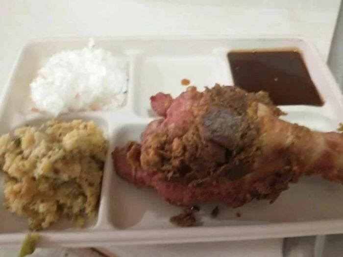 Unappetizing food tray with chicken, rice, gravy, and stuffing, highlighting unappealing meal presentation.