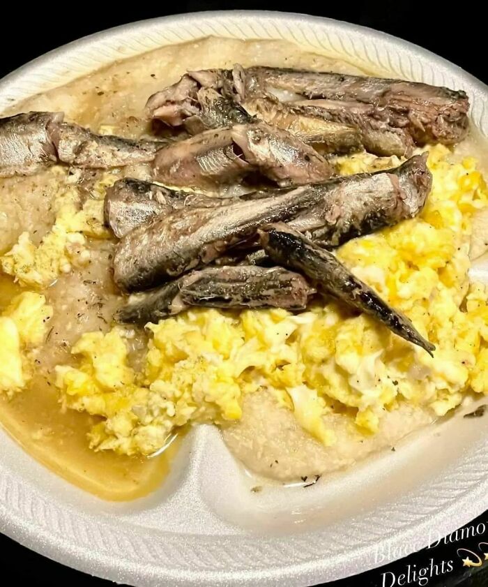 Unappetizing meal of scrambled eggs and fish on a paper plate.