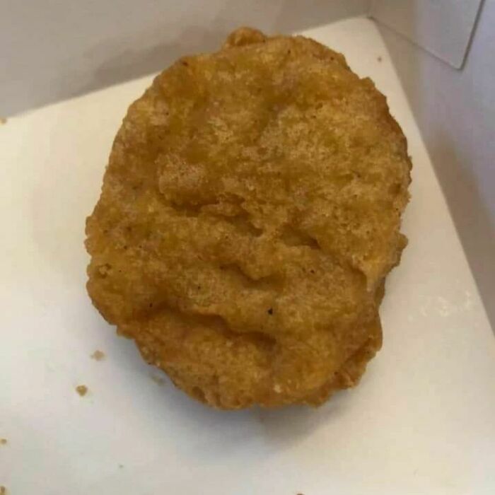 Unappetizing chicken nugget with a funny expression.