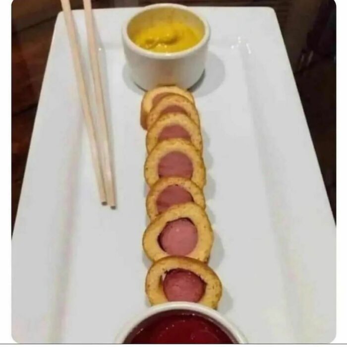 Unappetizing food on a plate with mustard and ketchup, featuring sliced sausage.
