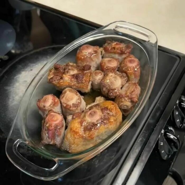 Unappetizing cooked meat pieces in a glass dish on a stovetop.