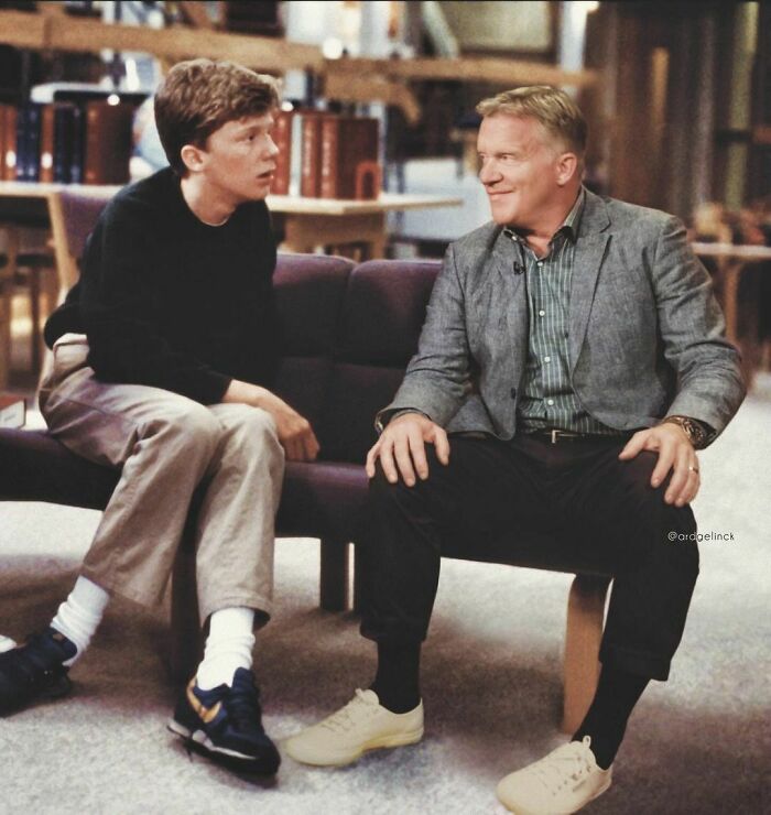 Two men, one younger and one older, sit on a couch having a conversation. Celebrities photoshopped together.