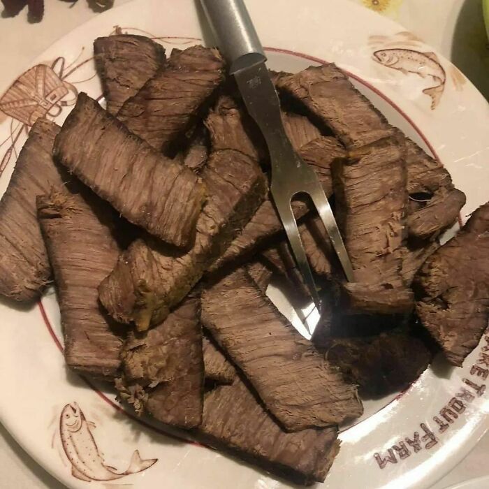 Unappetizing food photo of overcooked beef slices on a plate with a fork.