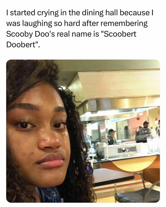 Young adult in a dining hall crying from laughter, capturing the mixed emotions of students living the best and worst life.