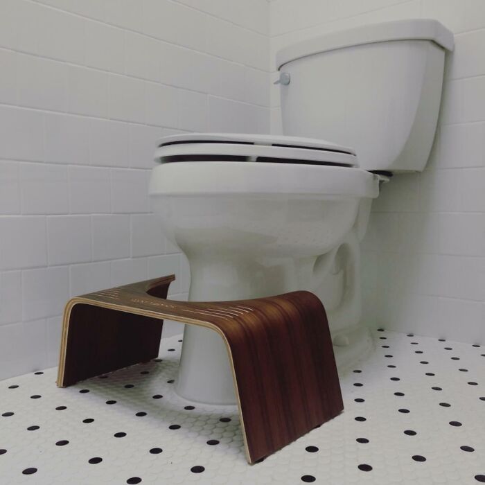 Bathroom product with a wooden toilet stool on a tiled floor.