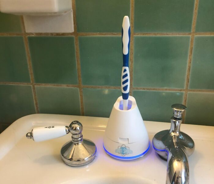Toothbrush in a glowing holder beside a sink, showcasing a top-rated bathroom product.