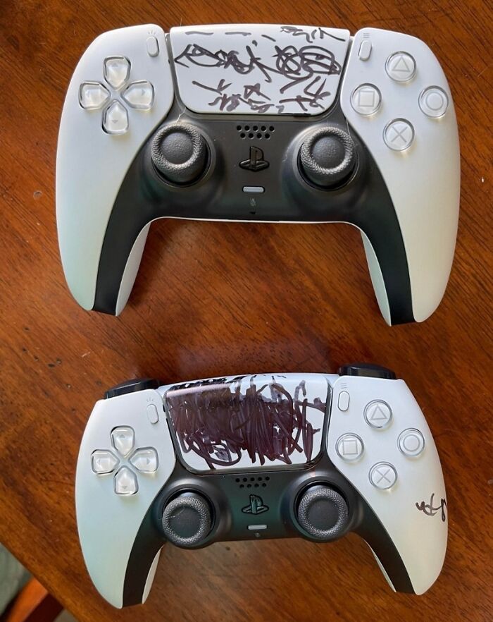 Two PlayStation controllers with black marker scribbles on the touchpads, showing parents having a pretty miserable day.
