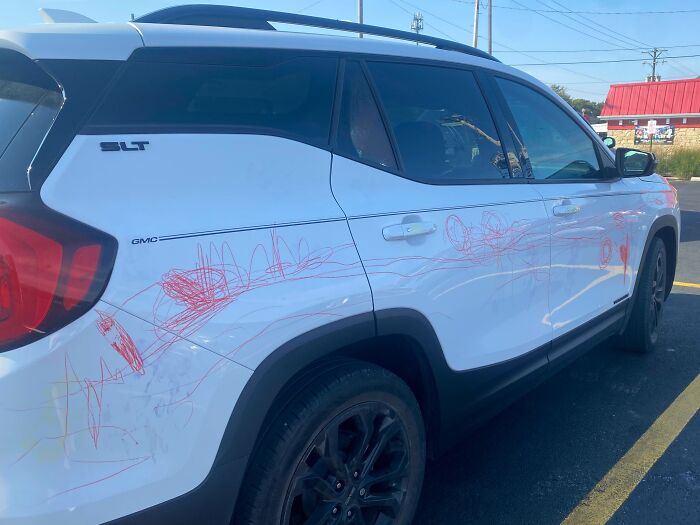 White GMC SUV with red crayon scribbles all over the side, showing parents having a pretty miserable day.