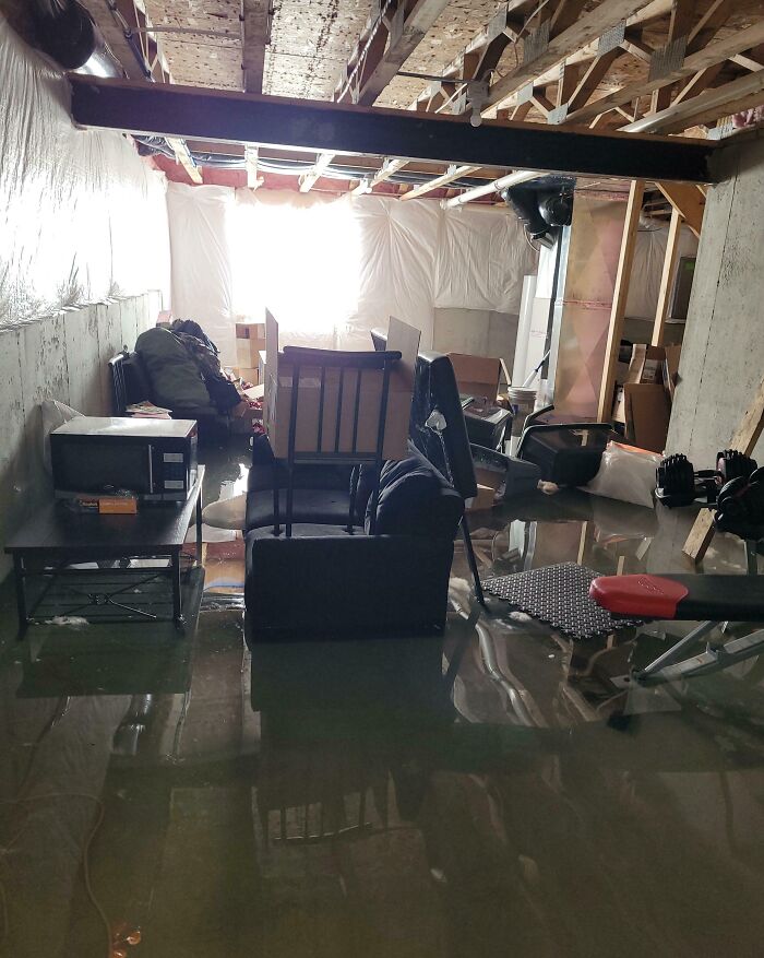 Flooded basement with scattered furniture and exercise equipment, depicting a scene reflecting parents having a miserable day.