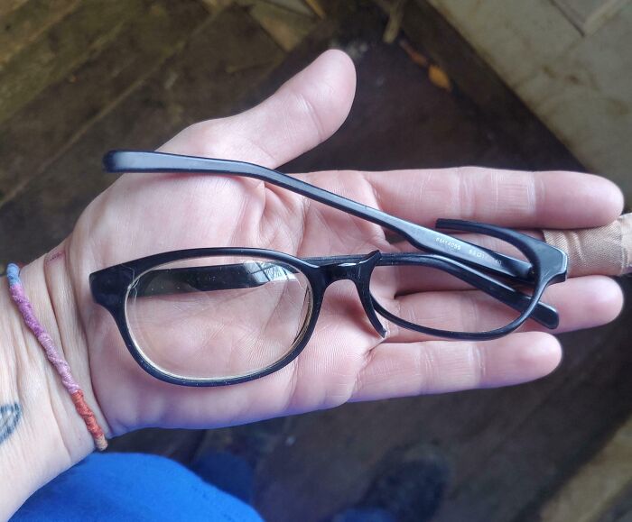Close-up of a hand holding broken eyeglasses symbolizing parents having a pretty miserable day with frustrating challenges.