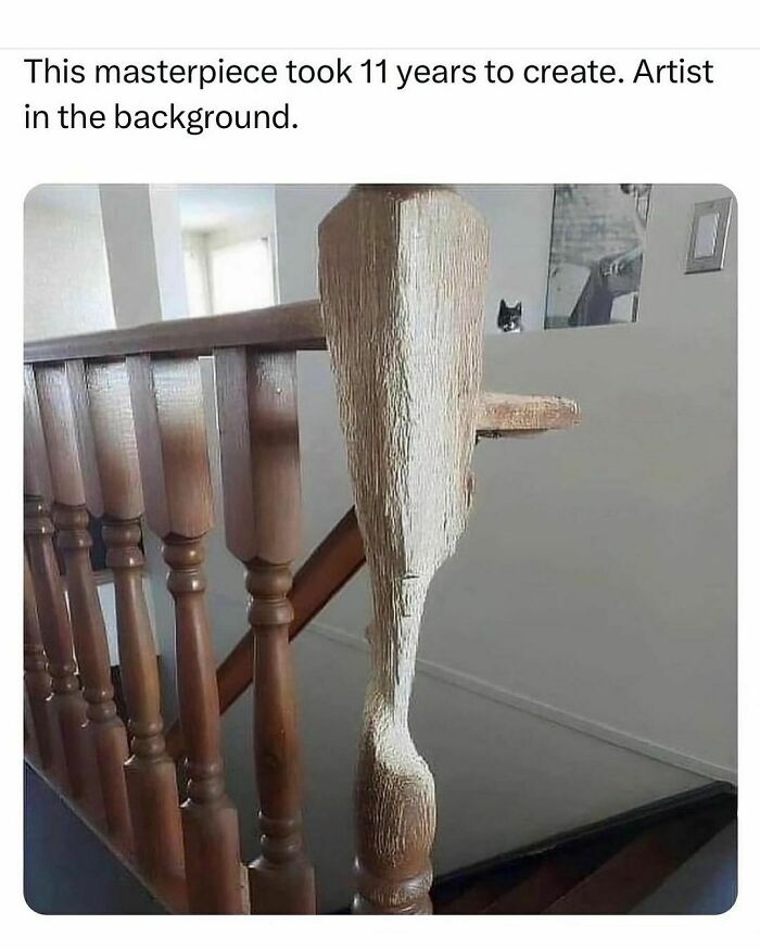 Carved wooden stair post resembling a whale with a cat peeking in the background, funny animal meme concept.