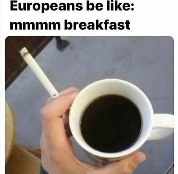 Hand holding a cigarette and a cup of coffee, with text reading "Europeans be like: mmmm breakfast." Relatable meme humor.