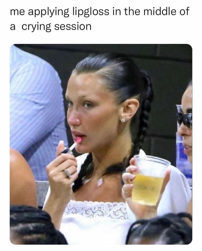 Woman with braided hair applying lipgloss during an emotional moment, illustrating relatable random memes about shared experiences.