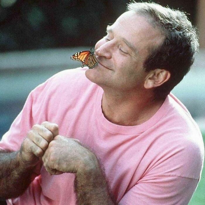 Person in a pink shirt smiling with a butterfly on their nose, capturing nostalgic '90s essence.