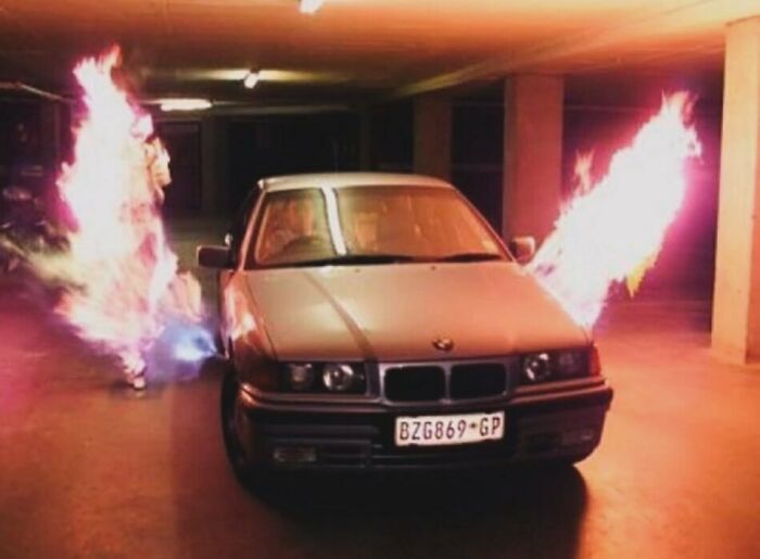 BMW in a parking garage with vibrant flames in the background, capturing the essence of nineties nostalgia.