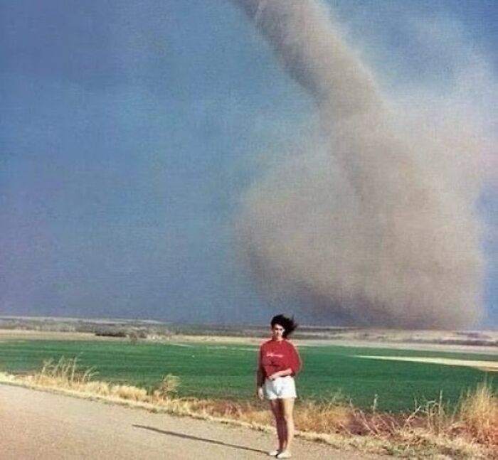 Person standing near a tornado, capturing a moment of nineties nostalgia and excitement.