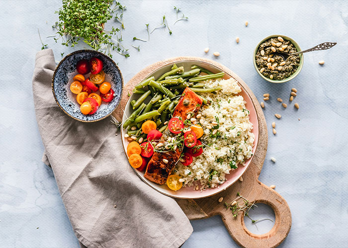 Healthy meal with salmon, green beans, cherry tomatoes, and quinoa on a wooden board, illustrating strange childhood realities
