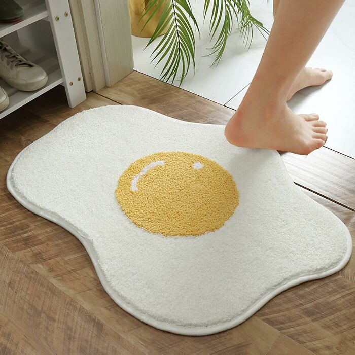 Person stepping on a quirky fried egg shaped rug, one of the random things with borderline genius design ideas.